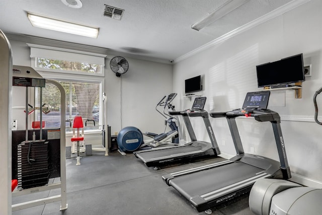 workout area with baseboards, visible vents, a textured ceiling, and ornamental molding