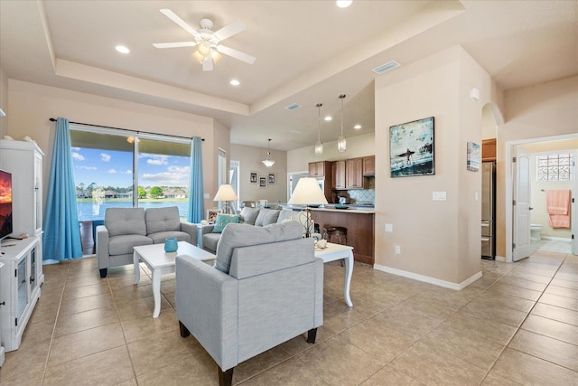 living room with arched walkways, light tile patterned floors, recessed lighting, a raised ceiling, and visible vents