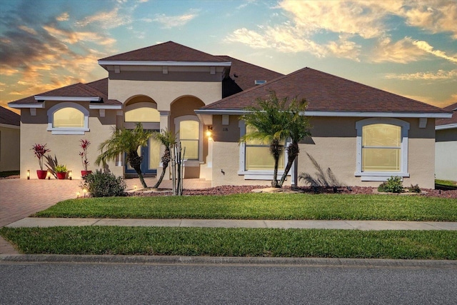 mediterranean / spanish home with stucco siding, decorative driveway, and a front yard