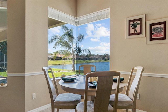 dining space featuring a water view and baseboards