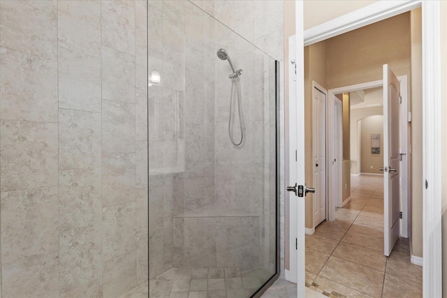 bathroom with tile patterned flooring, a shower stall, and baseboards