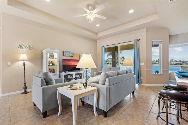 living area featuring baseboards, a tray ceiling, and recessed lighting