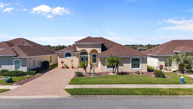 mediterranean / spanish-style house with decorative driveway, a front lawn, and stucco siding