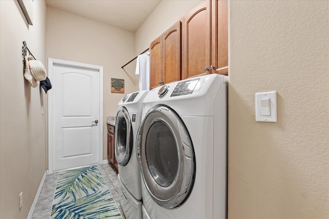 washroom featuring cabinet space, light tile patterned floors, baseboards, and washing machine and clothes dryer