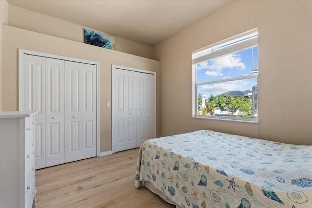 bedroom with multiple closets and light wood-type flooring