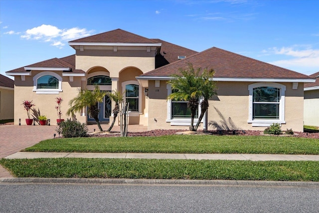 mediterranean / spanish house featuring a front lawn, decorative driveway, and stucco siding