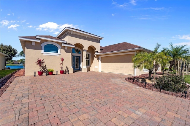 mediterranean / spanish-style house featuring a garage, decorative driveway, and stucco siding