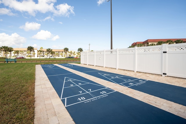 view of home's community with a yard, shuffleboard, and fence