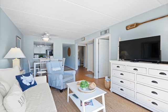 living area with visible vents and ceiling fan