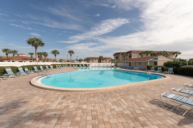 community pool with a patio and fence