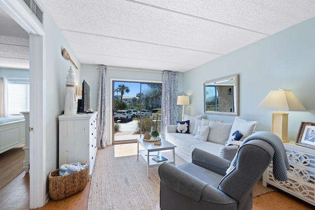 living area featuring visible vents, a textured ceiling, and wood finished floors