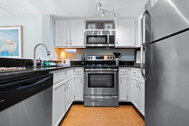 kitchen with light wood-style flooring, appliances with stainless steel finishes, white cabinets, and a sink