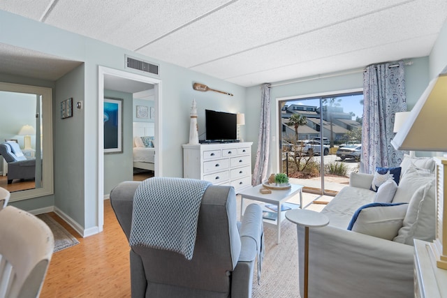 living area featuring visible vents, light wood-style flooring, and baseboards