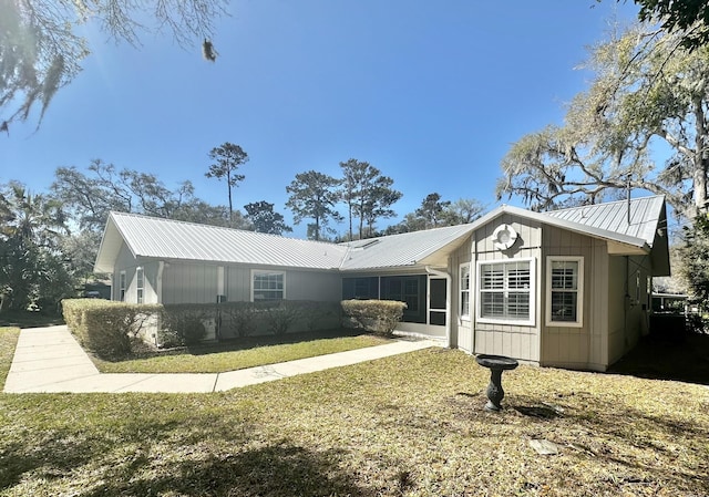 view of front of property featuring metal roof and a front yard