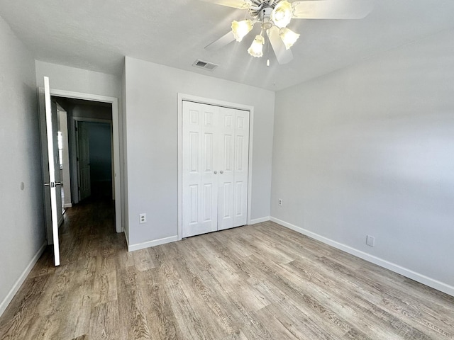 unfurnished bedroom with light wood-style flooring, baseboards, visible vents, and a closet