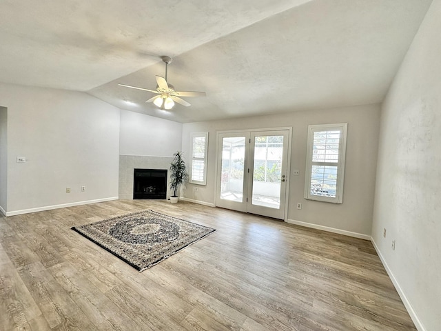 unfurnished living room featuring a tiled fireplace, vaulted ceiling, wood finished floors, and baseboards