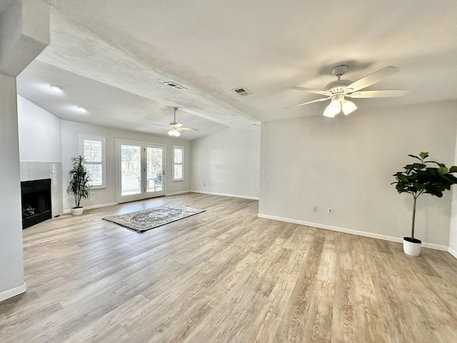 unfurnished living room with visible vents, a fireplace, and light wood finished floors