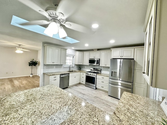 kitchen with decorative backsplash, light stone countertops, appliances with stainless steel finishes, and a sink