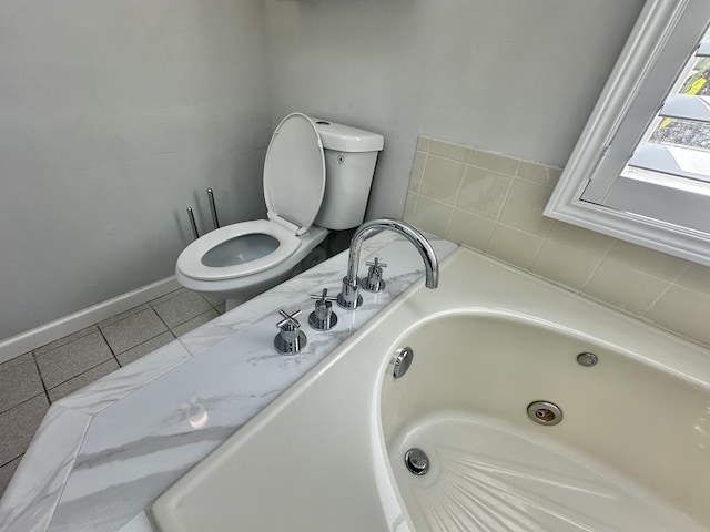 full bath with a tub with jets, baseboards, a sink, tile patterned flooring, and toilet