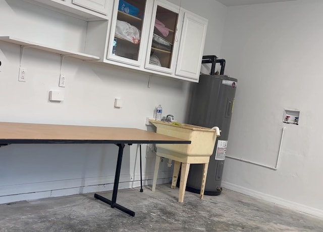 office space with unfinished concrete flooring, baseboards, and electric water heater