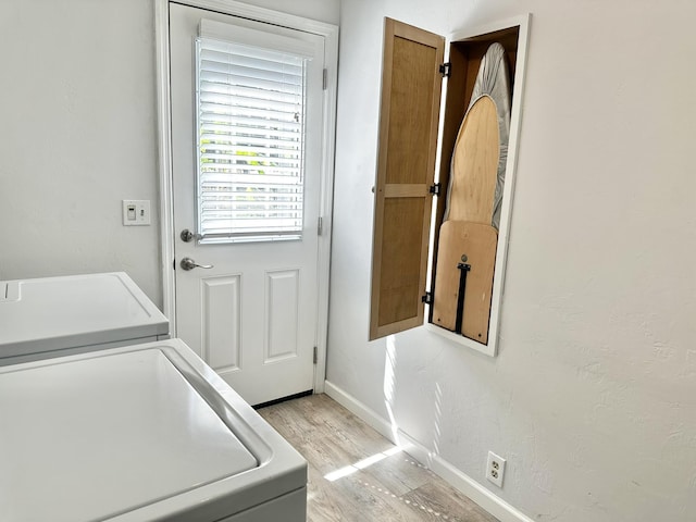 clothes washing area featuring laundry area, washer / clothes dryer, baseboards, and light wood finished floors