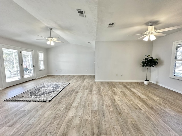 unfurnished living room featuring visible vents, lofted ceiling, a healthy amount of sunlight, and wood finished floors