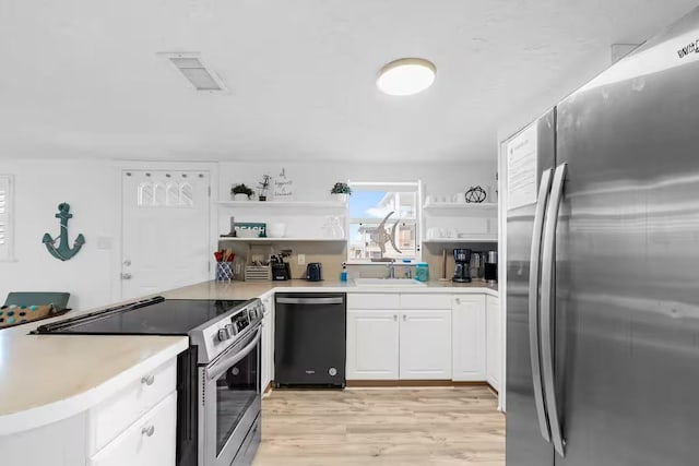 kitchen featuring sink, light hardwood / wood-style flooring, kitchen peninsula, white cabinets, and appliances with stainless steel finishes