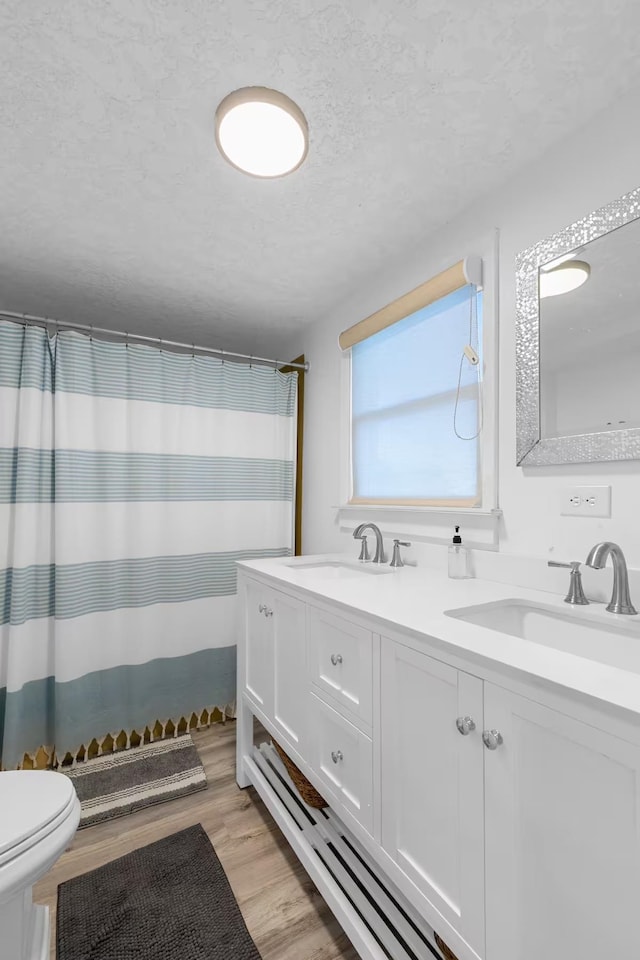 bathroom featuring a shower with curtain, vanity, wood-type flooring, and a textured ceiling