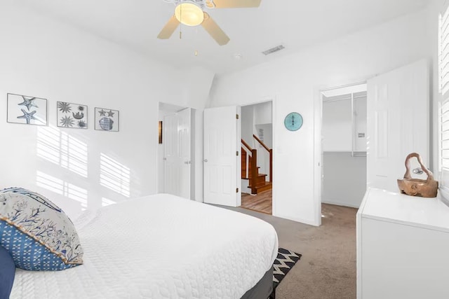 carpeted bedroom featuring a walk in closet, vaulted ceiling, a closet, and ceiling fan