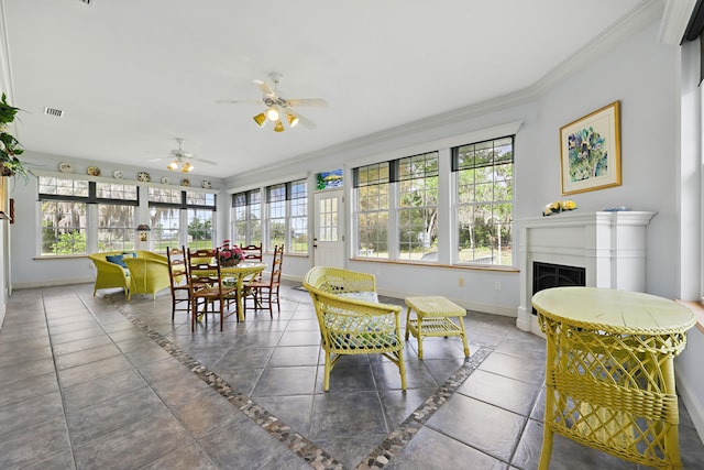 sunroom featuring ceiling fan, a fireplace, and a wealth of natural light