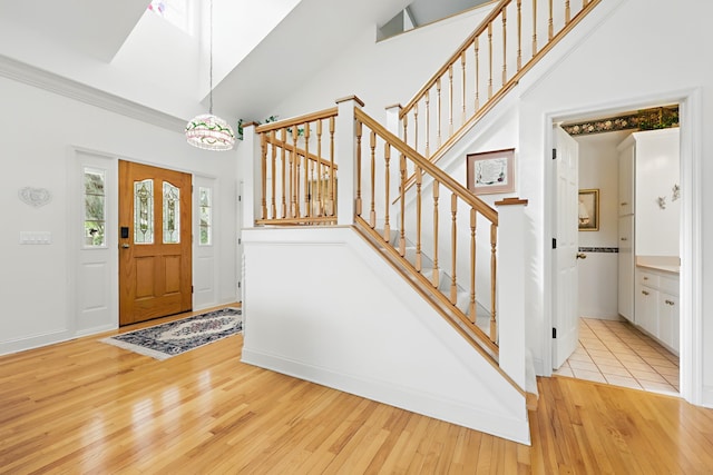 entryway featuring high vaulted ceiling, wood-type flooring, baseboards, and stairs