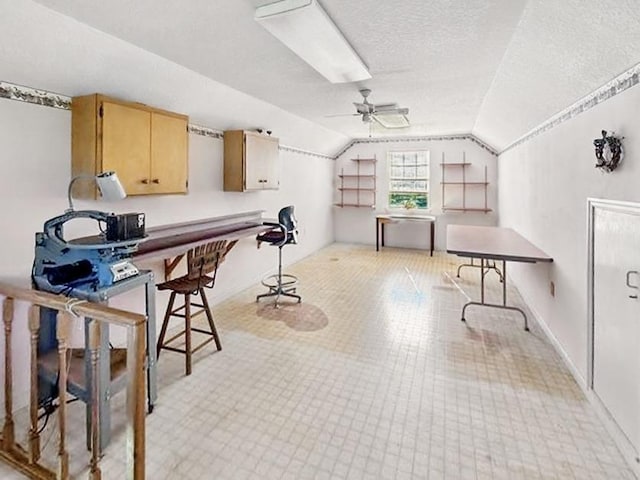 office space featuring lofted ceiling, ceiling fan, and a textured ceiling