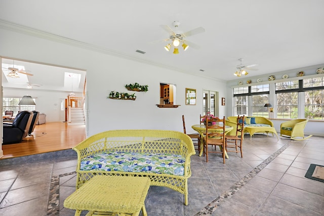 tiled living room with stairway, visible vents, ornamental molding, and a ceiling fan