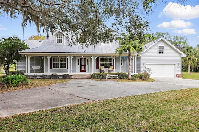 view of front of house featuring covered porch, a front yard, metal roof, a garage, and driveway