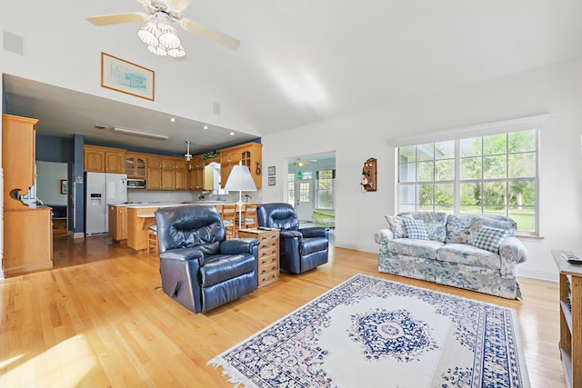 living room featuring vaulted ceiling, baseboards, a ceiling fan, and light wood-style floors