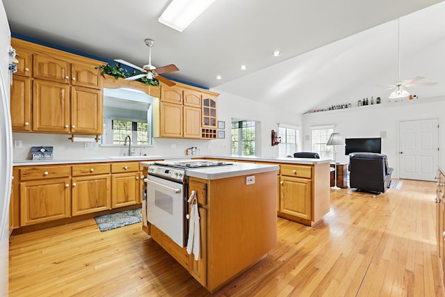 kitchen with lofted ceiling, light countertops, stove, a kitchen island, and a sink