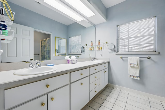 bathroom with a skylight, tile patterned floors, a sink, and double vanity