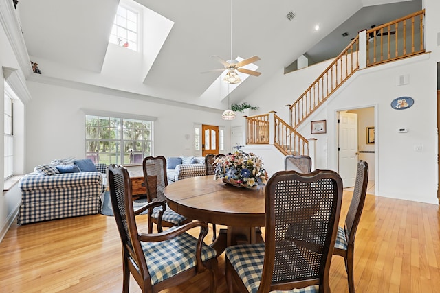 dining space featuring light wood-type flooring, ceiling fan, stairway, and a skylight