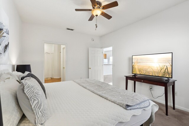 bedroom with connected bathroom, ceiling fan, and light carpet