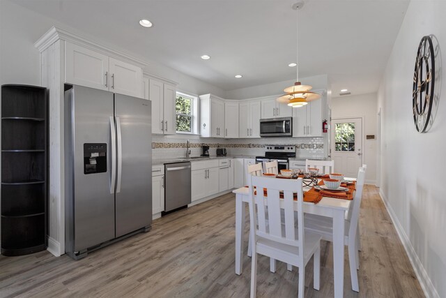 kitchen featuring pendant lighting, white cabinetry, plenty of natural light, and stainless steel appliances