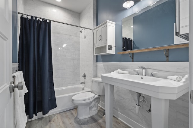 bathroom with hardwood / wood-style floors, toilet, shower / bath combo with shower curtain, and tile walls