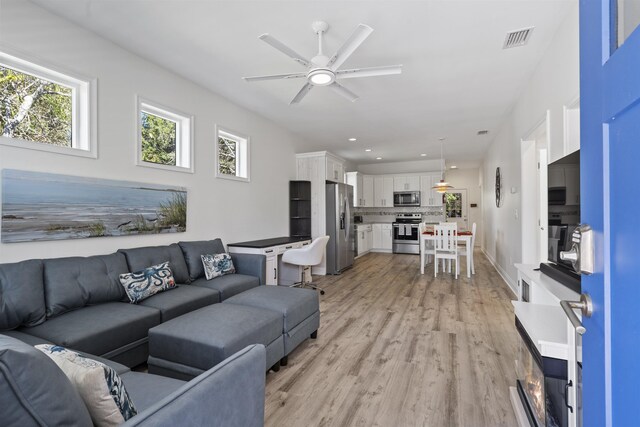 living room with light hardwood / wood-style flooring and ceiling fan