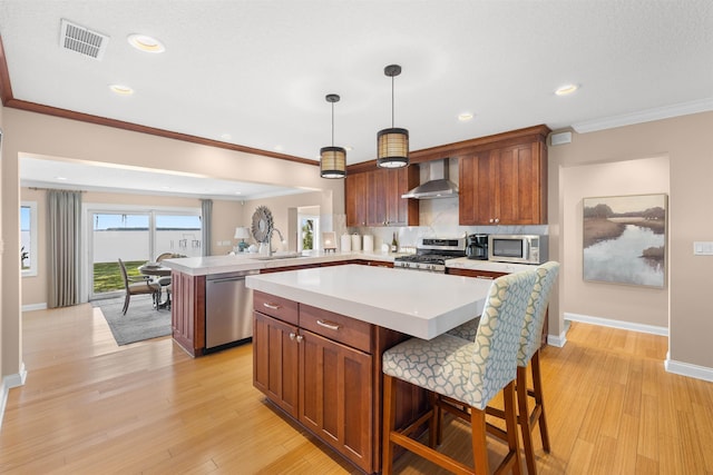 kitchen featuring light countertops, visible vents, a peninsula, wall chimney exhaust hood, and stainless steel appliances