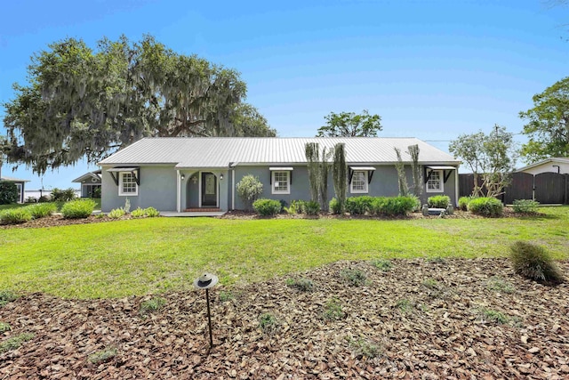view of front of home with a front lawn, metal roof, stucco siding, and fence