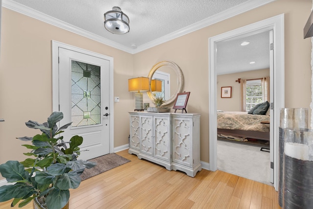 foyer entrance with ornamental molding, baseboards, light wood-style floors, and a textured ceiling