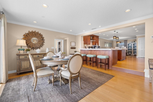 dining area featuring a textured ceiling, visible vents, light wood-style flooring, crown molding, and recessed lighting