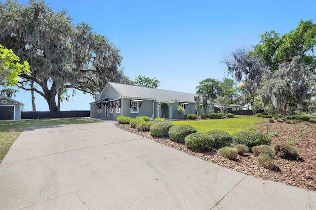 ranch-style house featuring metal roof, stucco siding, fence, and a front lawn