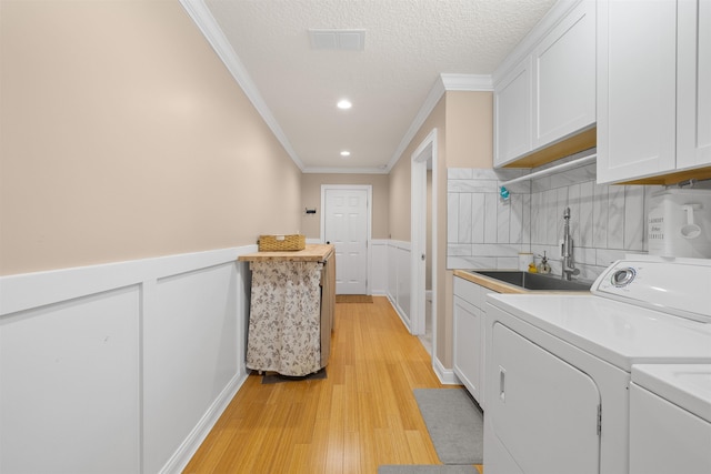laundry area featuring independent washer and dryer, wainscoting, cabinet space, and a sink