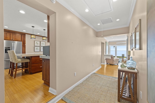 hallway featuring attic access, recessed lighting, ornamental molding, baseboards, and light wood finished floors
