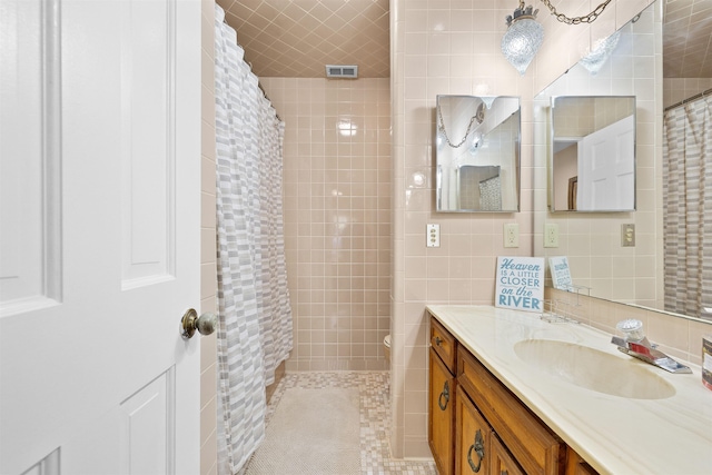 bathroom with tile walls, visible vents, toilet, vanity, and a shower with curtain